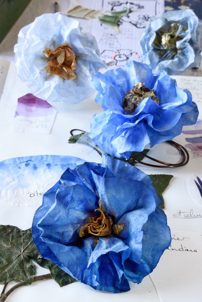 Fleurs en papier washi peint en bleu sur un carnet de recherches